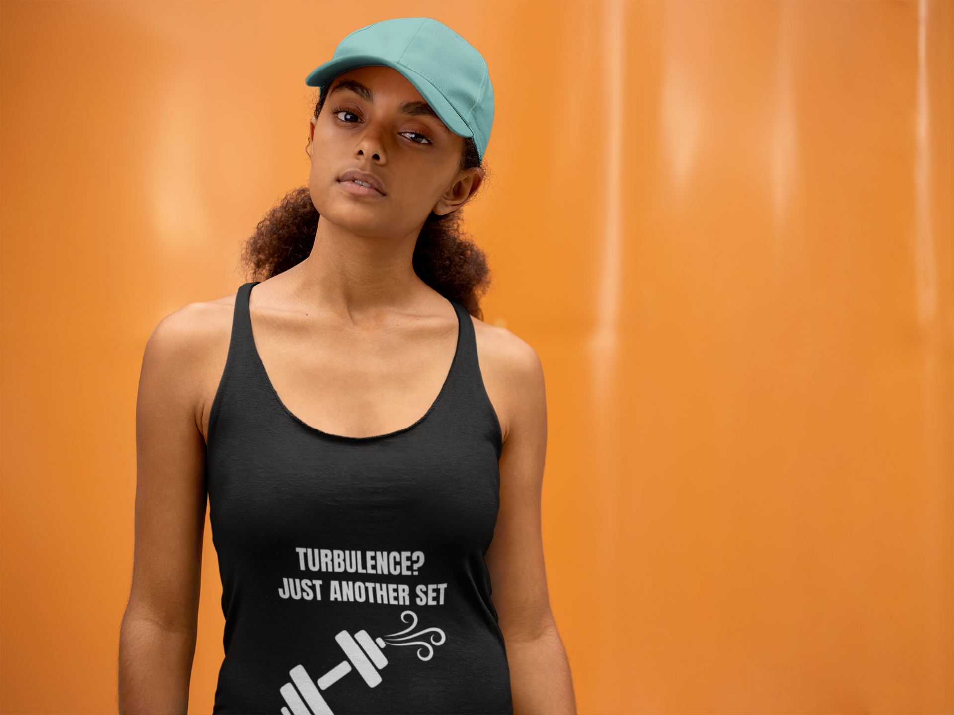 Technical tailored fit racerback tank in Vintage Black with teal cap against orange wall - capsule wardrobe travel fitness