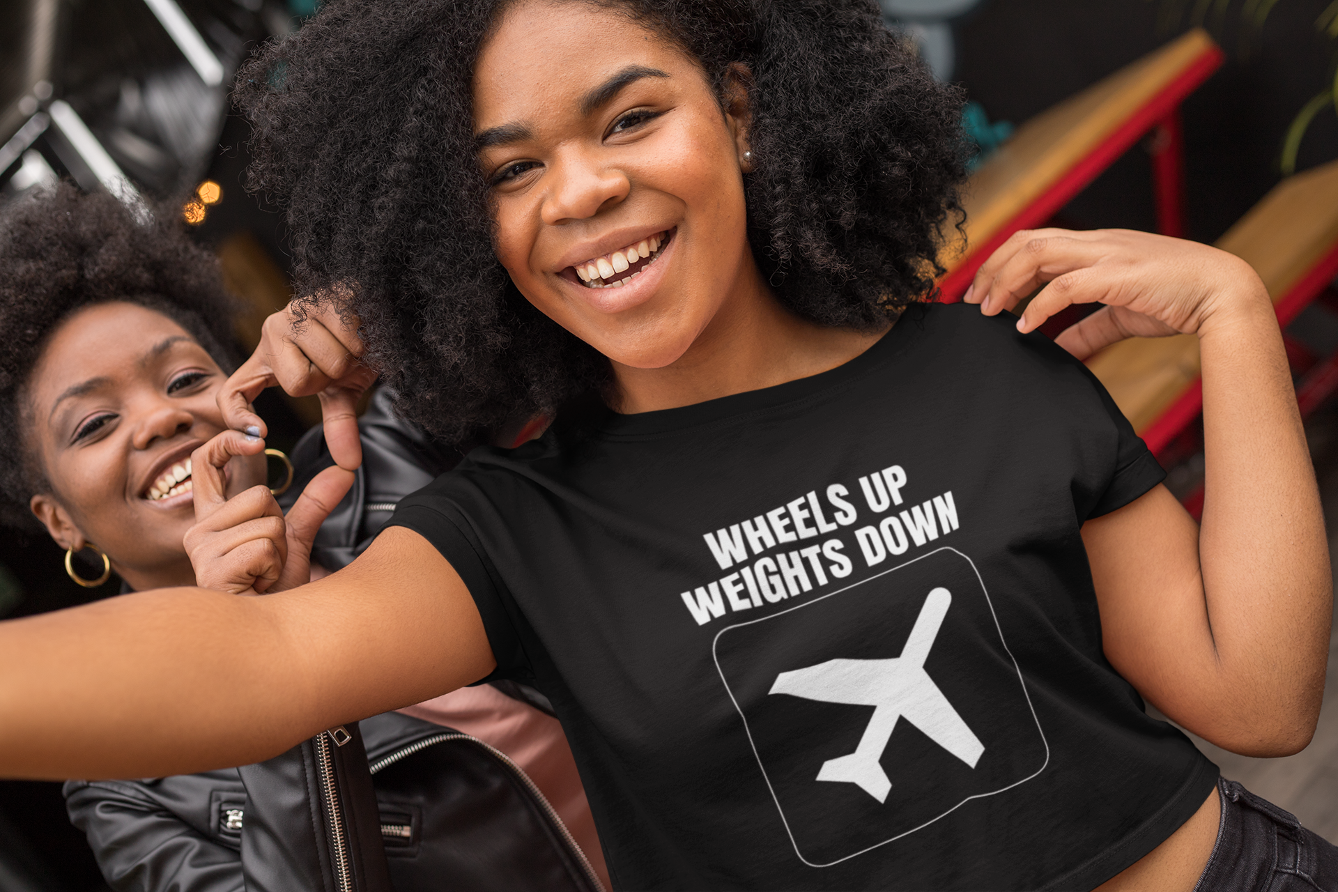 Two female travelers in black Wheels Up Weights Down crop tops hanging out after flight layover training