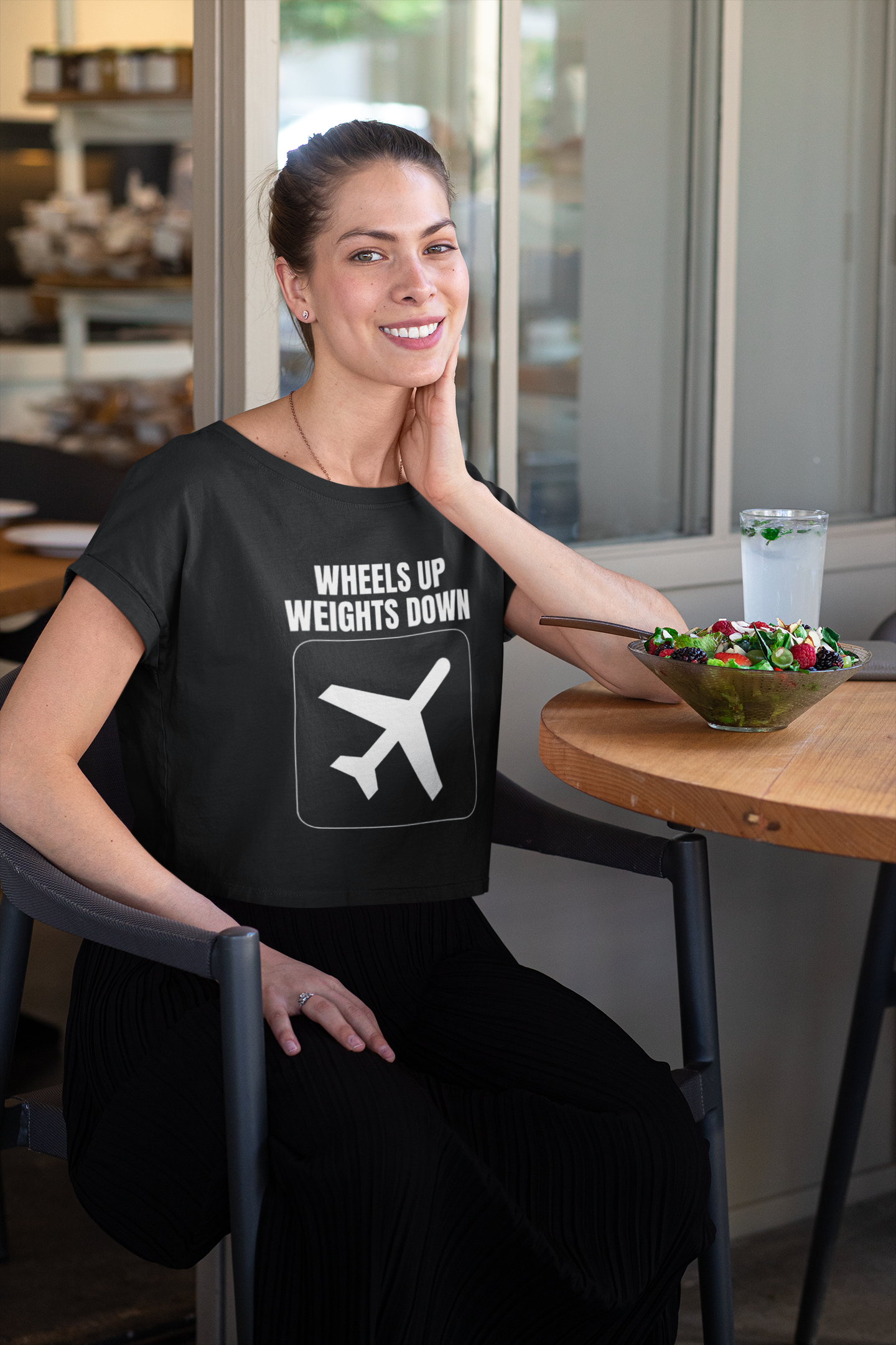 Traveling professional in black Wheels Up Weights Down crop top enjoying a healthy meal between flights